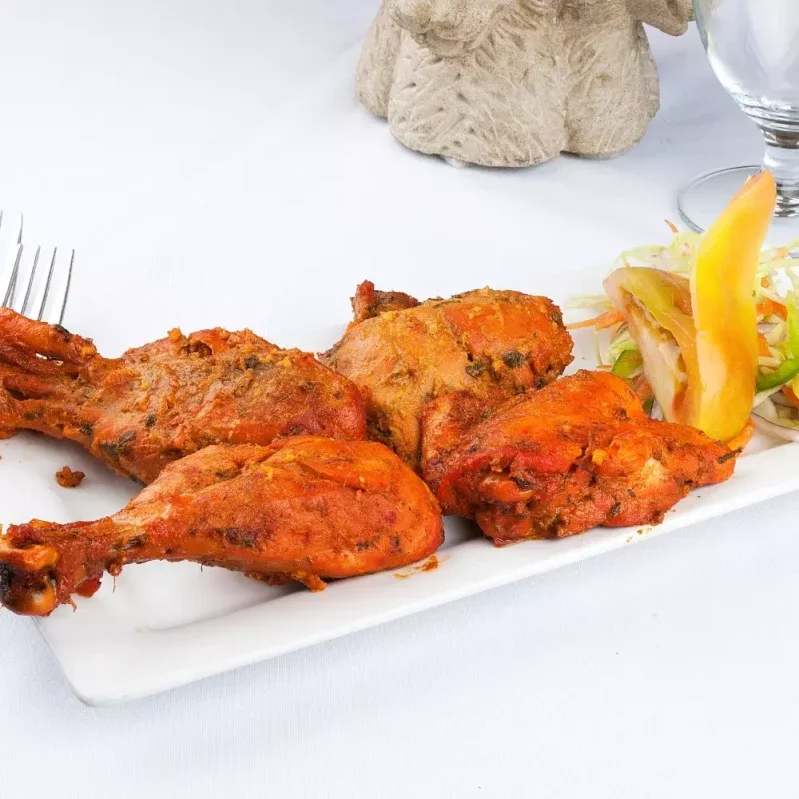 Tandoori Chicken at Indian BBQ & Grill - Signature clay oven dish in Red Deer, AB. Chicken marinated in yogurt and spices, served with mint chutney.